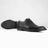 Maßgefertigter klassischer Herrenschuh Vitallo Brogue – schwarzes Boxcalf und Chevreau, schwarze Ledersohle – Paaransicht schräg mit Sohle