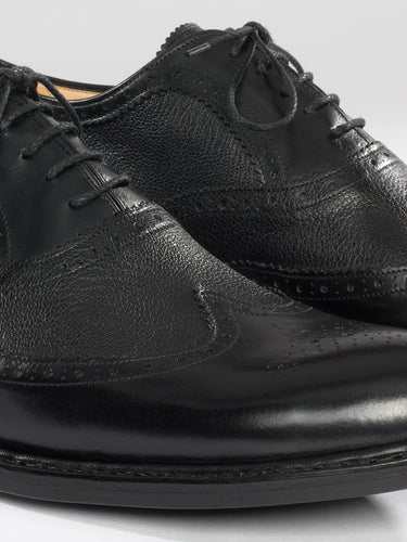 Maßgefertigter klassischer Herrenschuh Vitallo Brogue – schwarzes Boxcalf und Chevreau, schwarze Ledersohle – Paaransicht schräg von vorn
