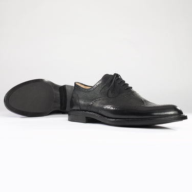 Maßgefertigter klassischer Herrenschuh Vitallo Brogue – schwarzes Boxcalf und Chevreau, schwarze Ledersohle – Paaransicht schräg mit Sohle